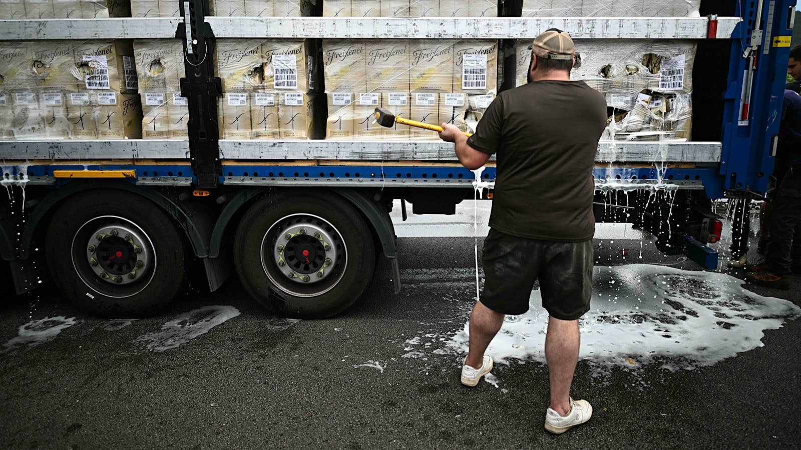 A man swings a hammer at cases of Cava.